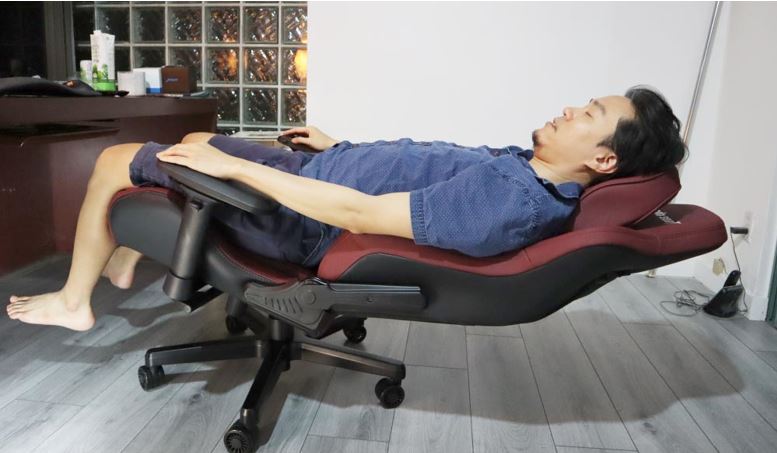 a man sleeping in a red gaming chair